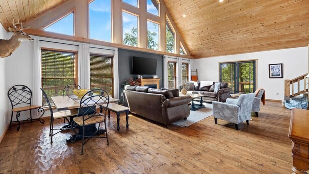 Un vaste espace de vie doté d’un haut plafond, de grandes fenêtres et d’un plancher en bois.