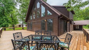 Une cabane en bois dotée d’une terrasse, de grandes fenêtres et d’un espace salon extérieur.