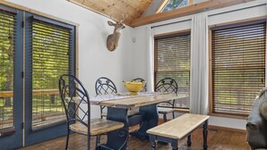 Un coin repas avec une table en bois, des chaises et une tête de cerf accrochée au mur.