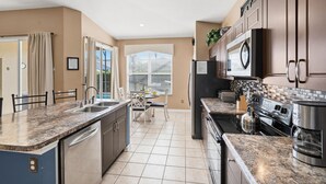 A kitchen with a central island, stainless steel appliances, and a view to the outside.