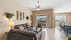 A living room with a sofa, coffee table, and a dining area with chairs and a table.