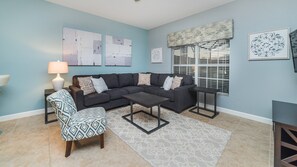 Relax in this inviting living room with a sofa, armchair, and side table, surrounded by artwork and a large window.