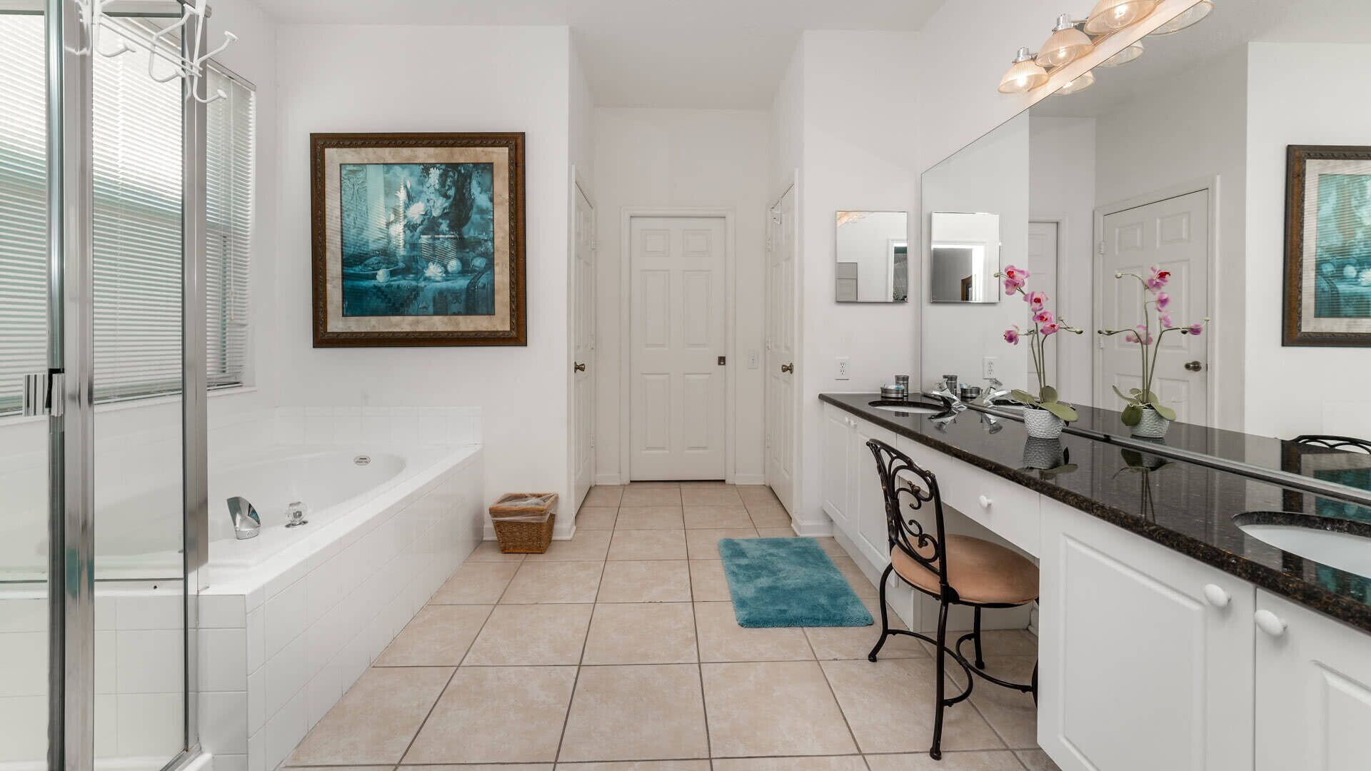 A modern bathroom with a bathtub, a vanity with a mirror, and a framed artwork on the wall.