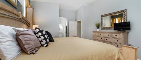 A bedroom with a bed, dresser, television, and a mirror.