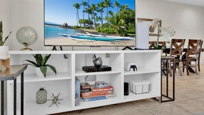 A living room with a flat-screen TV, a globe, and board games on shelves.