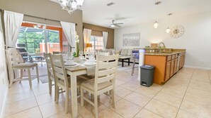 A dining area with a table set for four, a sofa, and a kitchen area with a sink and cabinets.