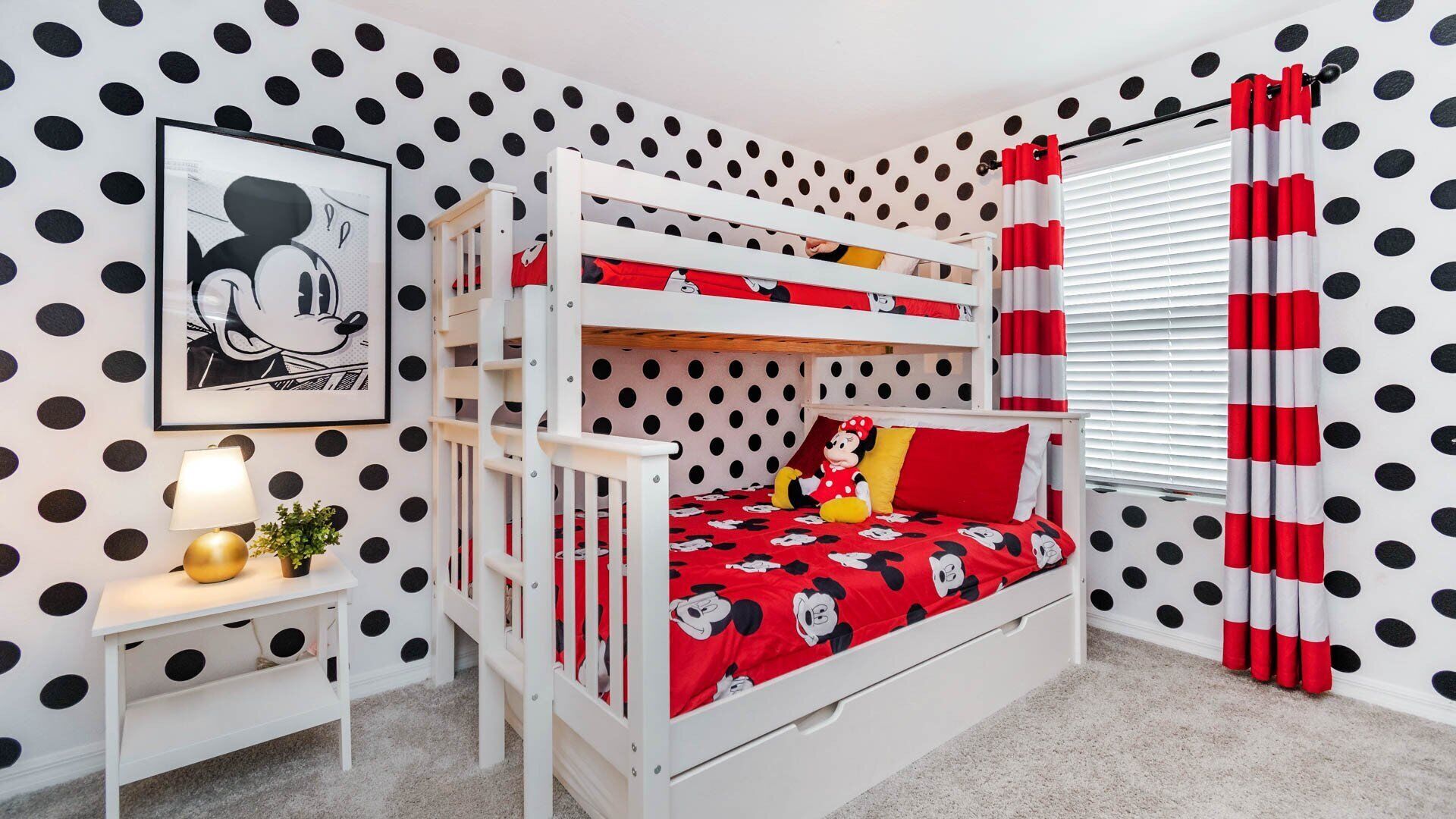 A bunk bed room with polka dot wallpaper, a Mickey Mouse poster, and red curtains.