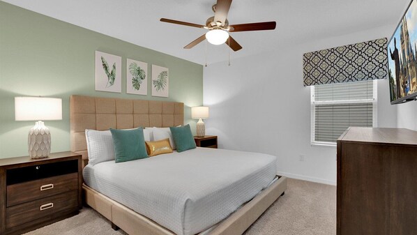 Un dormitorio con cama, mesitas de noche, ventilador de techo y decoración en la pared.