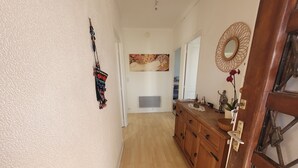 A hallway with a wooden cabinet, a decorative wall hanging, and a large painting. - Upper villa , 62m2,  3 pièces with see views,  garde and parking (Antibes)