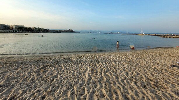 A beach with a rocky shoreline, calm water, and distant buildings. - Upper villa , 62m2,  3 pièces with see views,  garde and parking (Antibes)