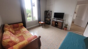 A living room with a sofa, a television, a bookshelf, and a window. - Upper villa , 62m2,  3 pièces with see views,  garde and parking (Antibes)