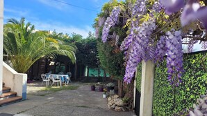 A courtyard with a table and chairs, a staircase, and purple flowering vines. - Upper villa , 62m2,  3 pièces with see views,  garde and parking (Antibes)
