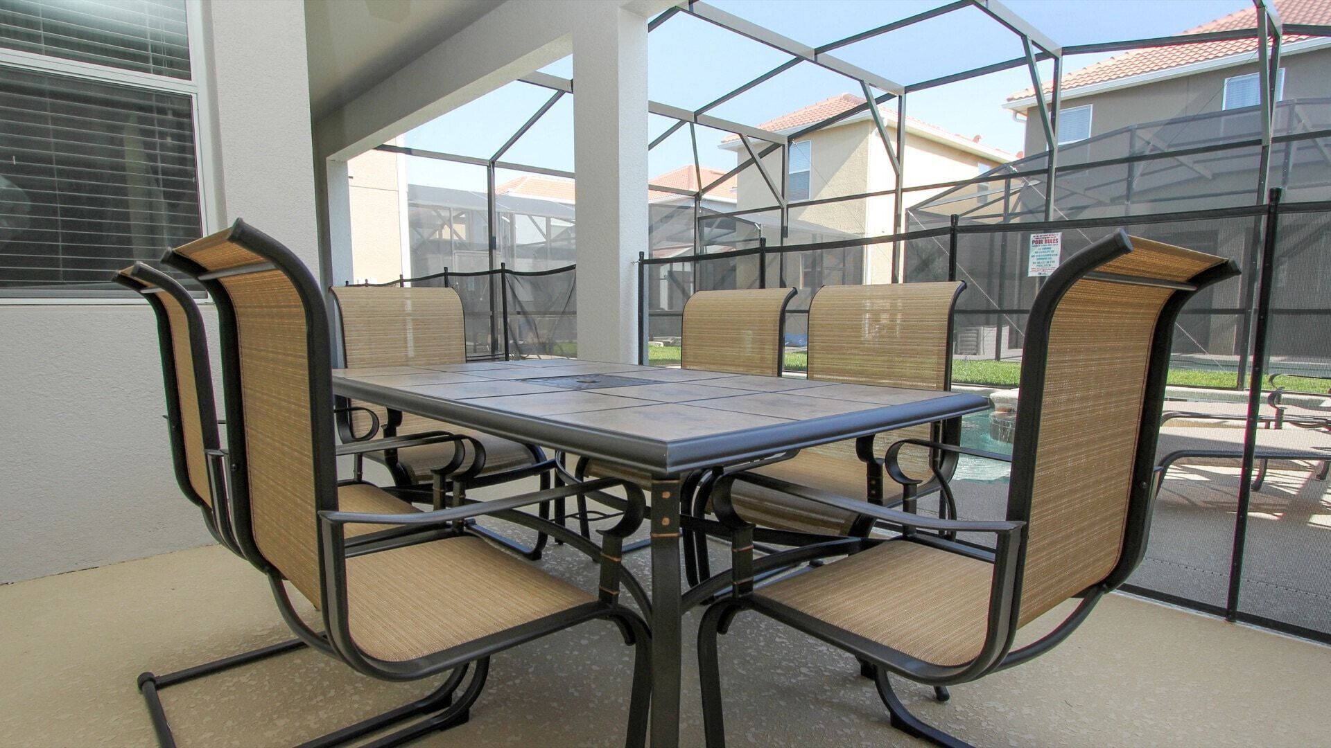 A patio with a glass-enclosed table and chairs, surrounded by a metal fence.