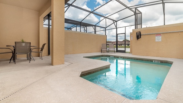 Una piscina interior con techo de cristal, rodeada de paredes color beige y amueblada con sillas y mesas.