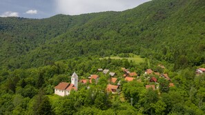 A village with traditional houses and a church surrounded by lush green hills.