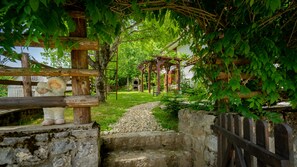 A rustic outdoor setting with a wooden pergola, a stone pathway, and a small brick oven. - Charming Holiday House in Velika Lesnica (Delnice)