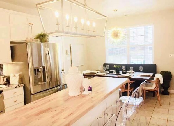 Une cuisine moderne dotĂ©e dâun plan de travail en bois, dâappareils Ă©lectromĂ©nagers en acier inoxydable et dâun coin repas avec une table et des chaises.