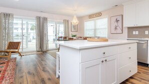 A spacious kitchen with a large island, white cabinetry, and a sign reading "BEACH HOUSE". - Newly renovated home across from the beach! (Carolina Beach)