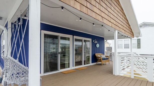 A covered deck with a blue wall, white railings, and a wooden ceiling. - Newly renovated home across from the beach! (Carolina Beach)