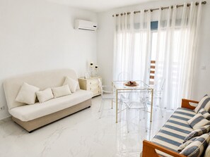 Ein stilvolles Wohnzimmer mit einer Couch, einem Glastisch und einem gestreiften Sofa.