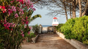A pathway leading to a beach with a lifeguard tower and lush greenery. - Villa Bay Pine - direct access to Pittulongu beach, wi-fi (Olbia)