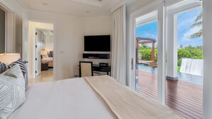 Habitación de hotel con cama, televisión, escritorio y vista a una piscina al aire libre.