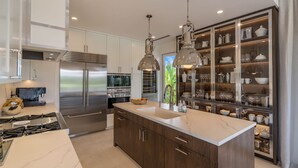 Una cocina moderna con electrodomésticos de acero inoxidable, armarios de madera e iluminación colgante.