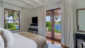 Un dormitorio con cama, televisión, escritorio y vista al océano.