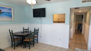 A dining area with a table and chairs, a ceiling fan, a mounted TV, and a kitchen area with cabinets. - Harrison Hotel Unit E
Pet Friendly
Ground Level (Murrells Inlet)
