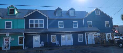 A two-story building with a blue exterior, a bar on the ground floor, and a parking lot in front.