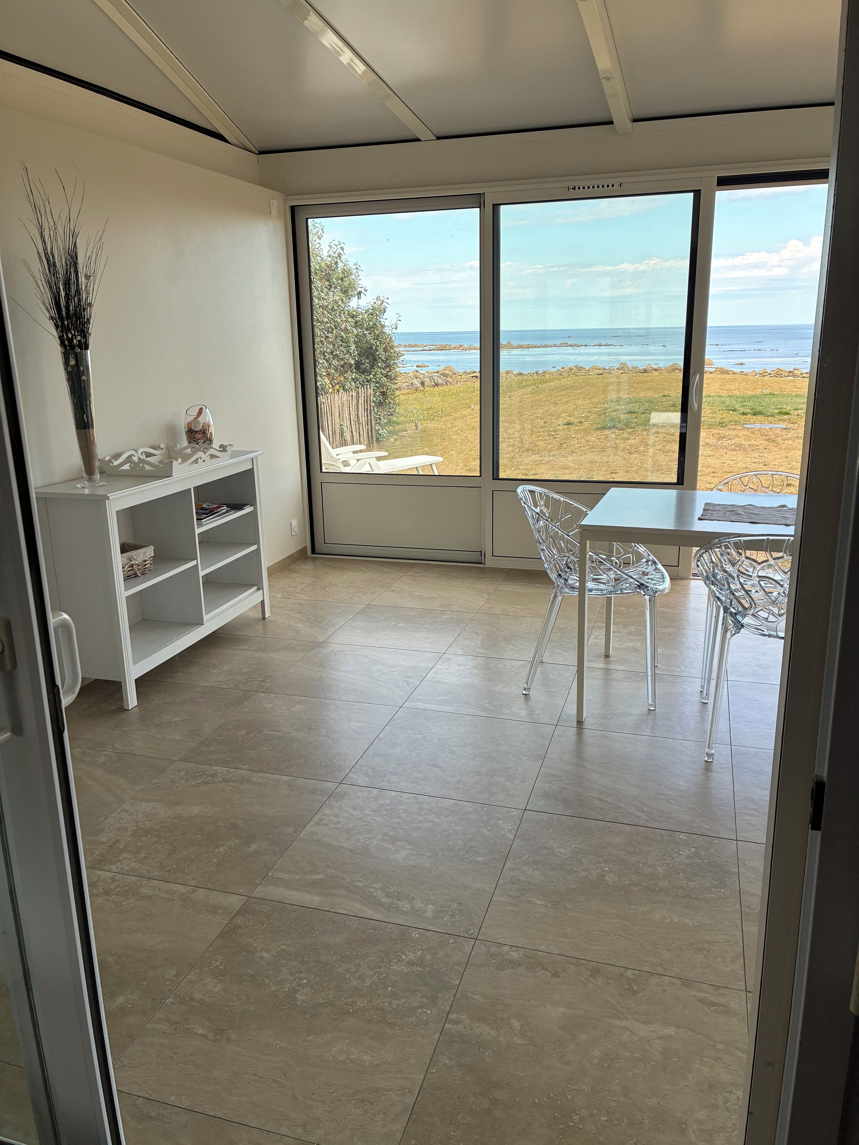 Una habitación con vista al mar, un armario blanco y una mesa con sillas.
