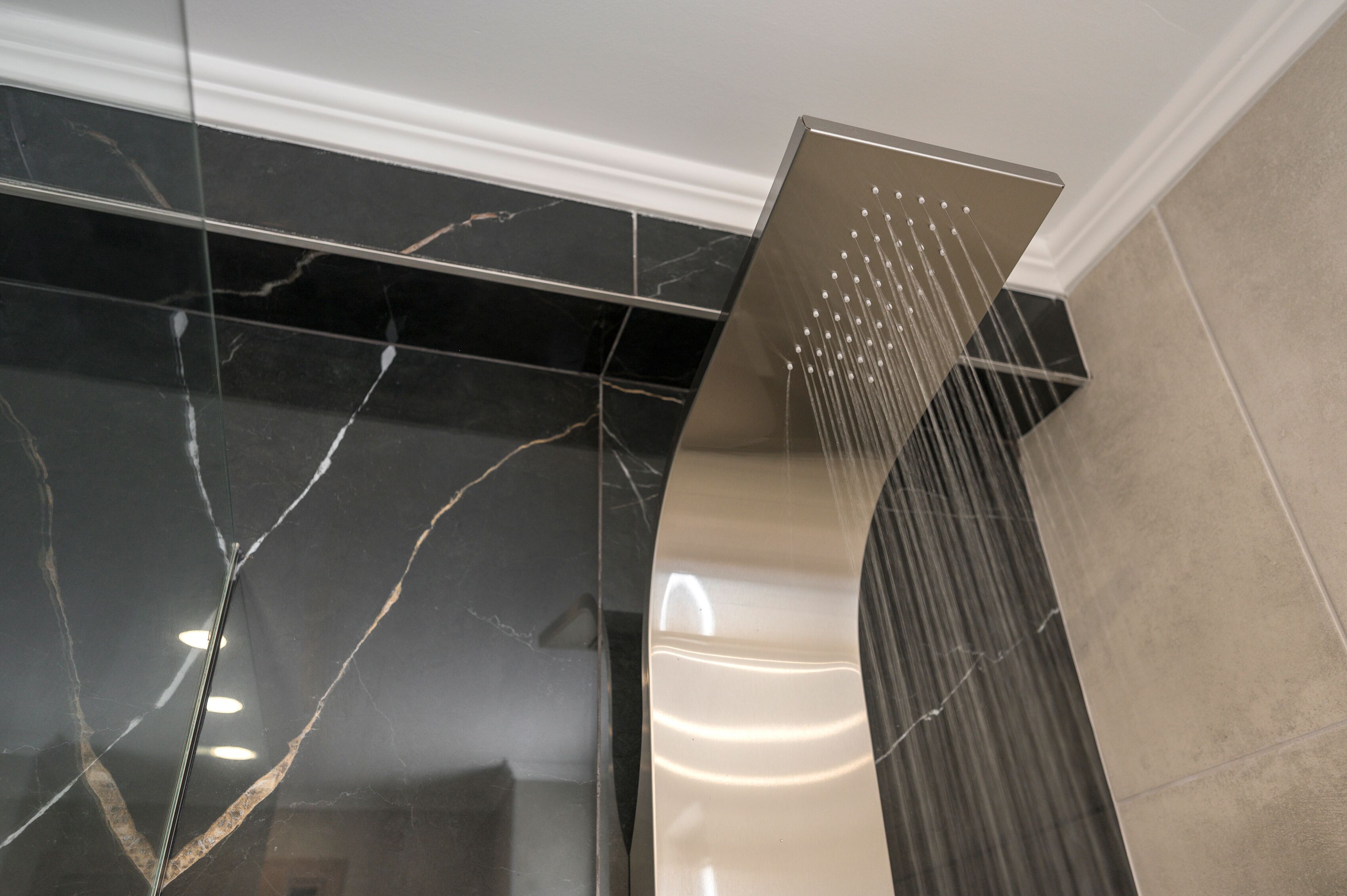 A modern shower with a sleek, metallic design and a curved water stream.