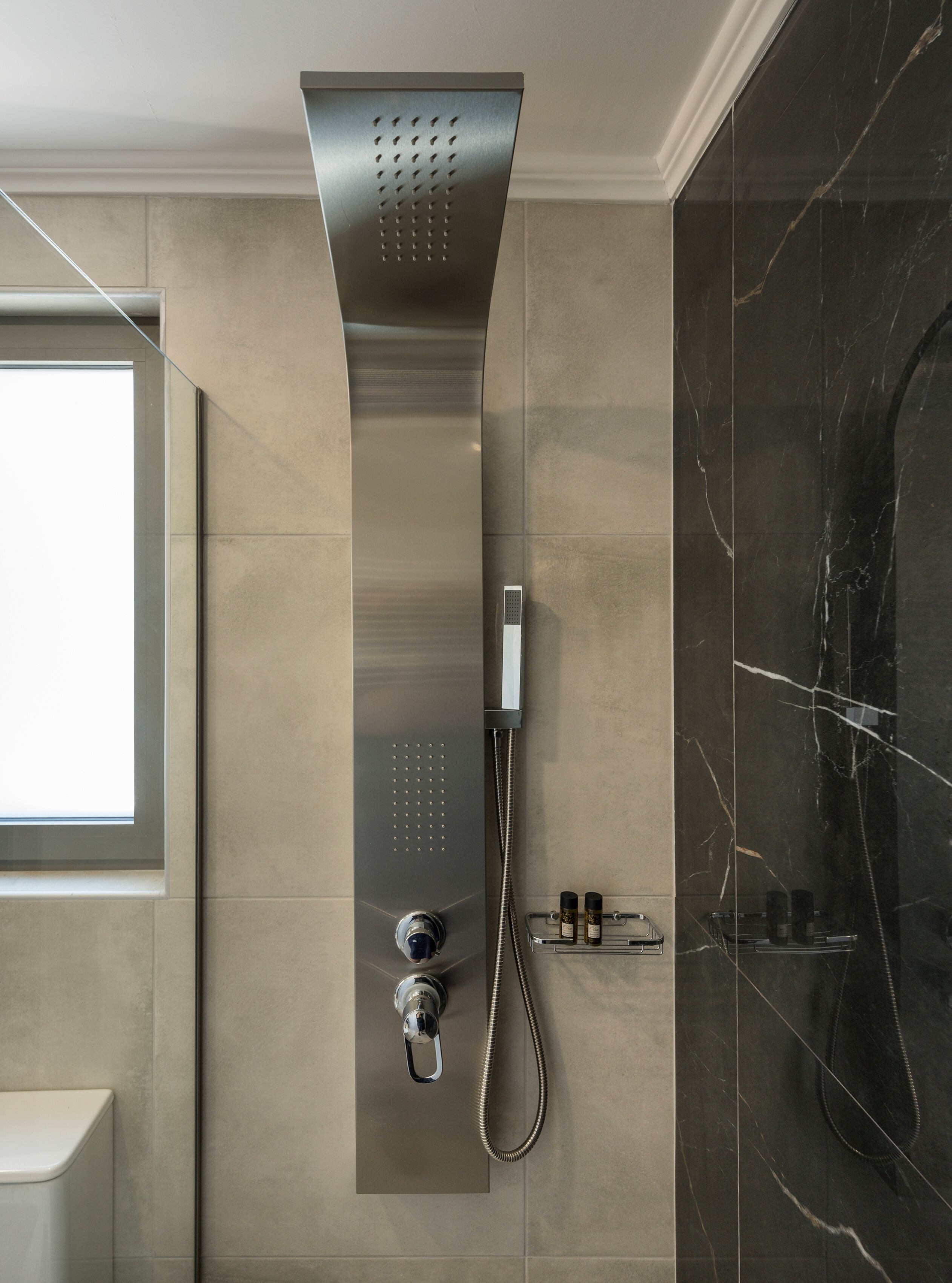 Een moderne douche met bedieningspaneel, douchekop en handdouche.