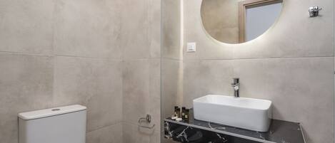 Une salle de bain moderne avec des toilettes, un lavabo et un miroir.