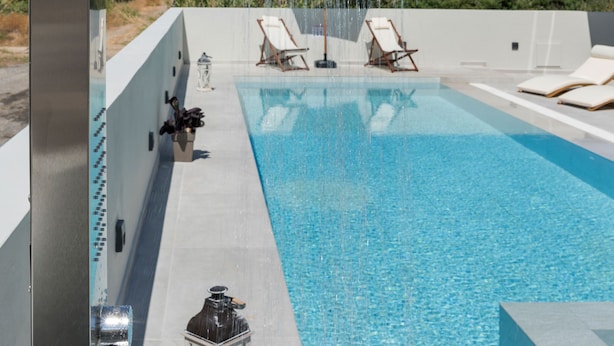 Una piscina en la azotea con ducha moderna, sillas de descanso y vistas despejadas del paisaje circundante.