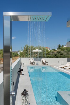 A rooftop pool with a modern showerhead, lounge chairs, and a clear view of the surrounding landscape. - Kallistefan (Kissamos)