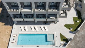 Un edificio moderno con varios balcones, piscina y mobiliario exterior.