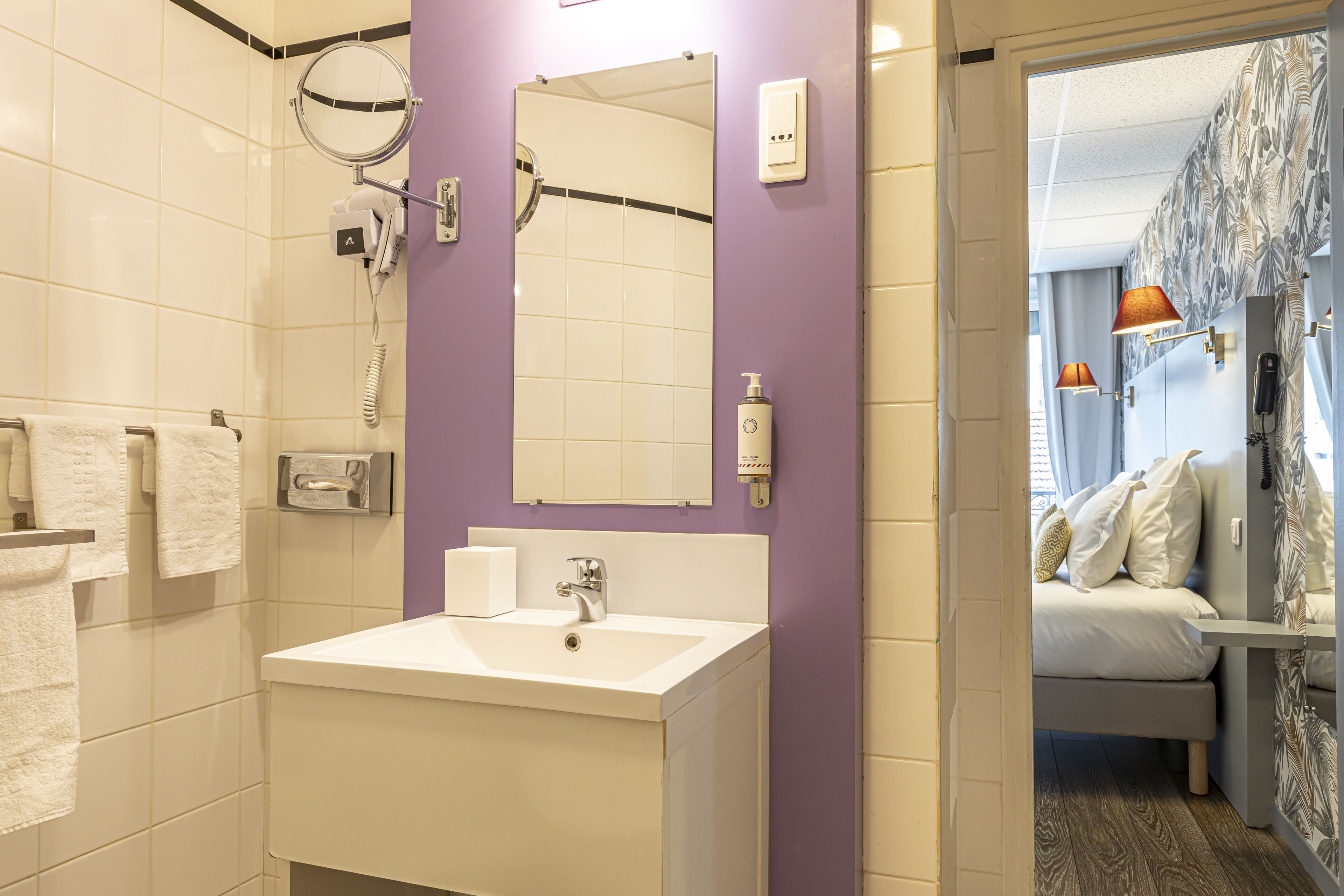A bathroom with a white sink, mirror, and towel rack.