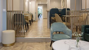 Un espace de restauration moderne avec des cloisons en bois, une table en marbre et un mélange de chaises bleues et beiges.