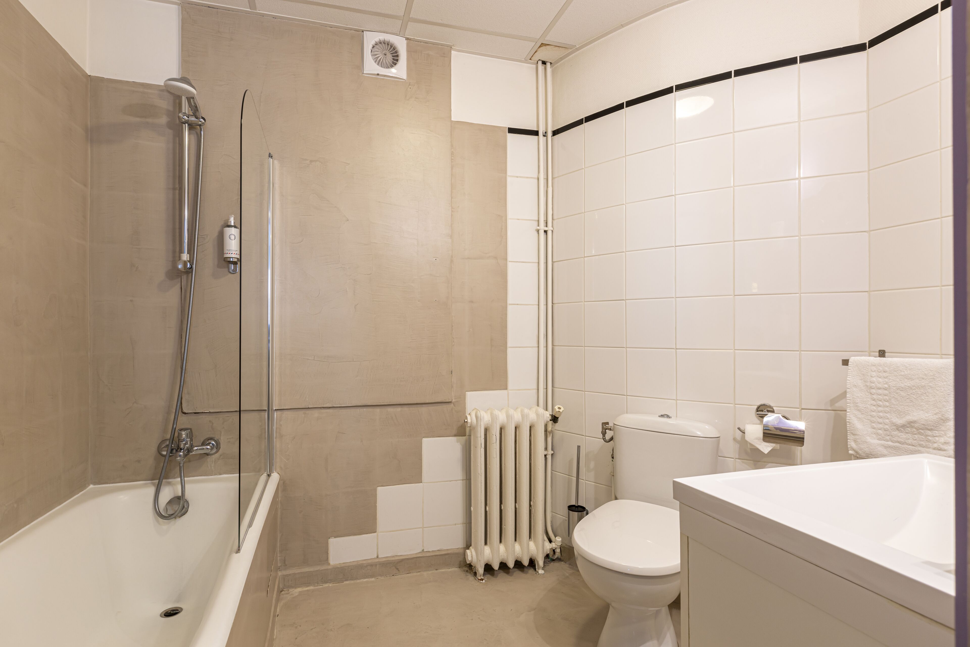 Une salle de bain moderne équipée d’une baignoire, de toilettes et d’un espace douche.