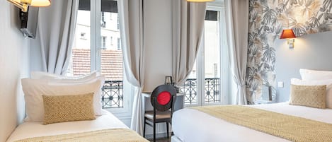 A hotel room with two beds, a desk, and a view of the city.