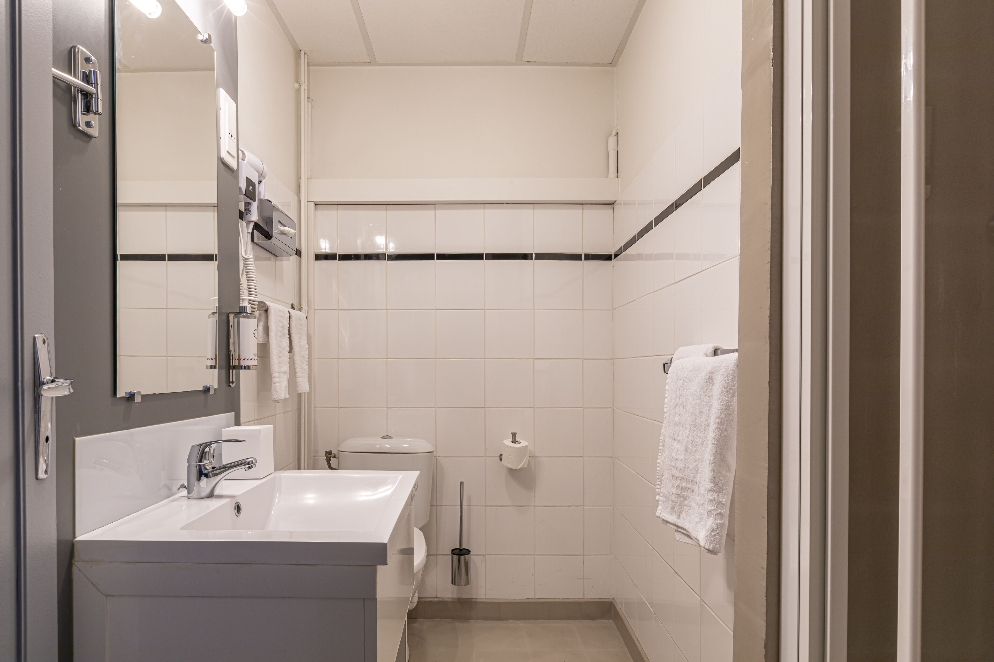 Un baño moderno con lavamanos, espejo, inodoro y zona de ducha.