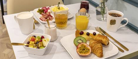 A breakfast table with a variety of food items, including fruits, pastries, and beverages.