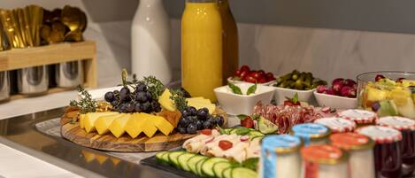 Un bufé con diversos quesos, frutas y embutidos.