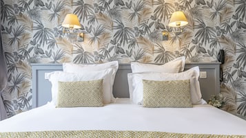 A hotel room with a bed, two wall-mounted lamps, and a patterned wallpaper.