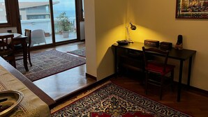A room with a dining area, a desk with a lamp, and a large window with a view of the outside. - MaLu House - (Messina)
