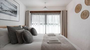A bedroom with a bed, pillows, a blanket, and a window with curtains.