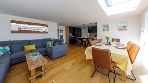 A modern living room with a sofa, coffee table, and dining area with chairs and a table. - Delightful Seaside Hideaway 5 Mins to Beach (Chichester)