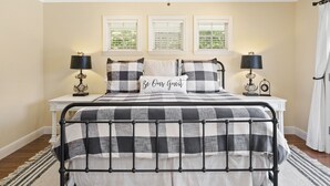 Quarto bem arrumado com cama, abajures e uma janela com persianas.