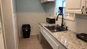 A compact kitchen with a granite countertop, a stainless steel sink, and white cabinetry. - Harrison Hotel Unit F
Pet Friendly 
Ground Level (Murrells Inlet)